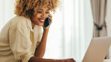 Woman on phone uses a laptop