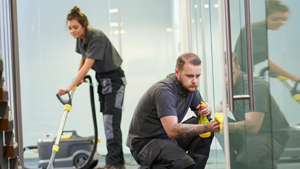 Two workers clean an office